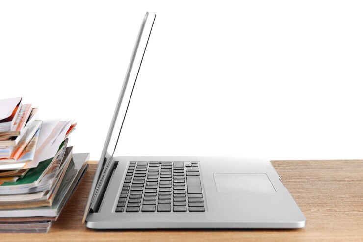 Foto laptop y pila de revistas en la mesa aislados en blanco