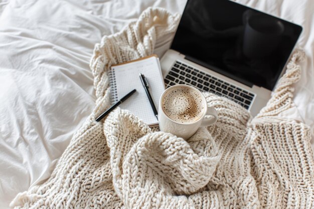 Laptop portátil y una taza de café en una cama en tonos beige Oficina en el hogar y concepto de pasatiempo