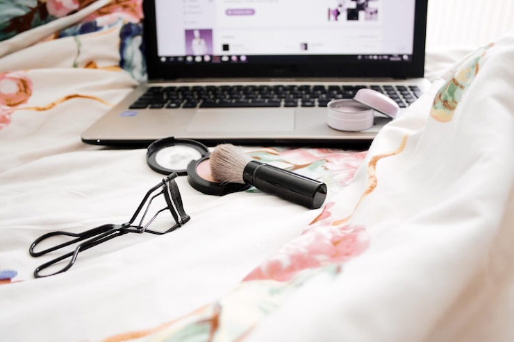 Foto laptop y producto de belleza en la cama en casa