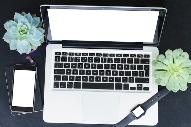 Laptop, relógio e telefone na mesa preta com espaço de cópia na tela