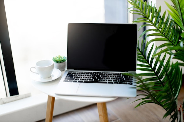 Laptop sem fio colocado na mesa com uma xícara de café no escritório