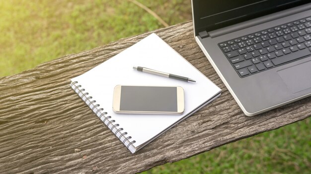 Foto laptop, smartphone, stift und buch auf holztisch.