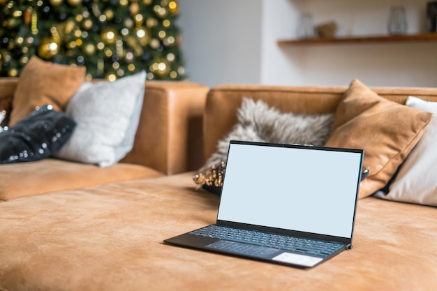 Laptop en el sofá con pantalla blanca aislada para maqueta en Navidad