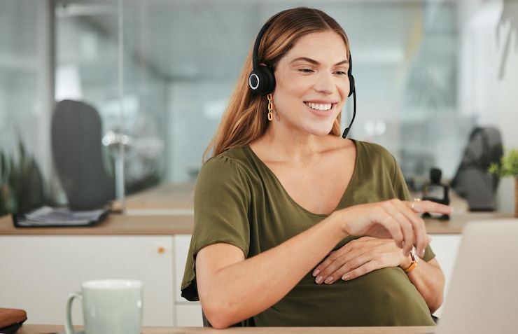 Foto laptop sorrindo e uma mulher grávida em um call center para atendimento ao cliente ou suporte com um fone de ouvido tech apontando e gravidez com uma jovem feliz empregada de negócios no local de trabalho como mãe
