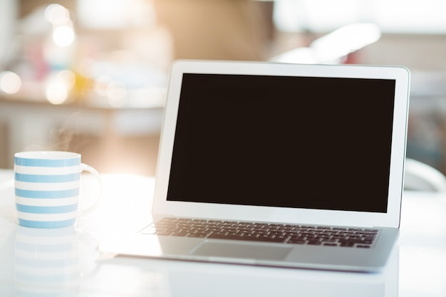 Laptop y taza de café sobre una mesa