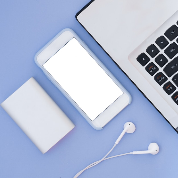 Laptop, Telefon, Kopfhörer und Power Bank auf blauem Grund. Flat Lay Komposition und Platz für Text. Draufsicht.