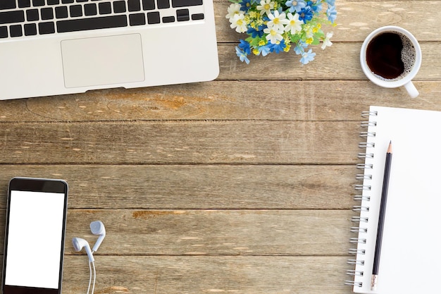 Laptop con teléfono inteligente y taza de café en la mesa del lugar de trabajo