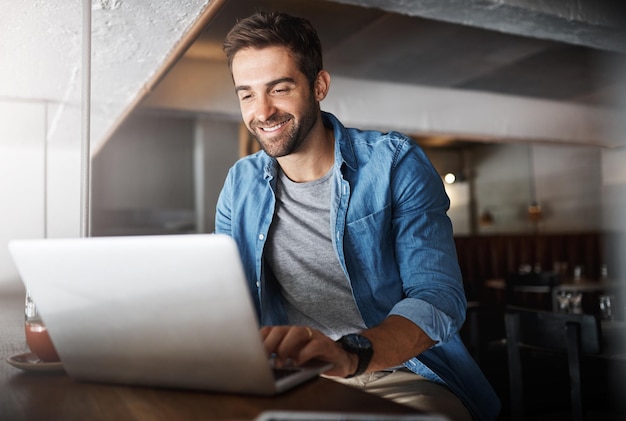 Laptop trabajo remoto y escribir con el hombre en la cafetería para la creación de redes o la investigación en línea Empleo independiente de computadora y sonrisa de cliente feliz en una cafetería o restaurante para la hospitalidad o el servicio