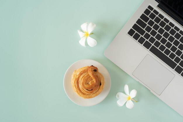 Laptop und Brot und Blumen auf grünem Hintergrund das Konzept des Online-Lernens