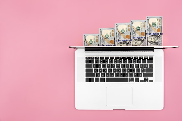 Foto laptop und dollarscheine auf farbigem hintergrund flach gelegt