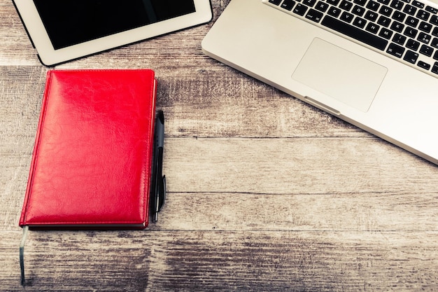 Laptop und ein Notizbuch zum Schreiben von oben auf einem hölzernen Hintergrund