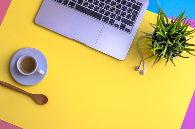 Laptop und Kopfhörer mit Kaffee und Anlage auf gelbem, blauem und purpure Hintergrund