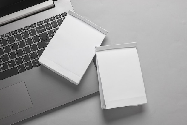 Laptop und Weißpapier Mittagessen-Taschen-Mockup auf grauem Hintergrund