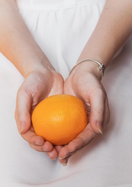 Laranja brilhante madura em mãos femininas macias