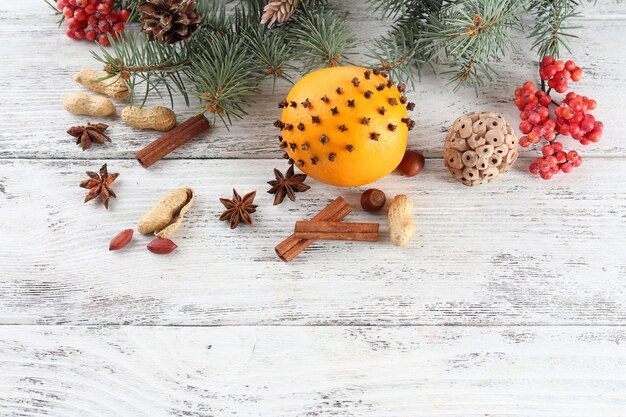 Laranja com especiarias, sorveira e raminho de pinheiro de Natal na cor de fundo de madeira