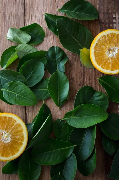 Laranja com folhas verdes em fundo de madeira