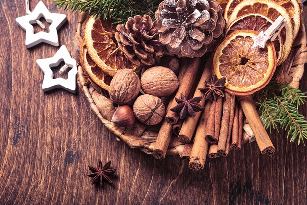 Laranja seca, anis estrelado, canela, pinhas e abeto em placa rústica na mesa de madeira. ideia de medley caseiro para clima e aroma de natal. natal amigo do ambiente com decorações naturais caseiras.