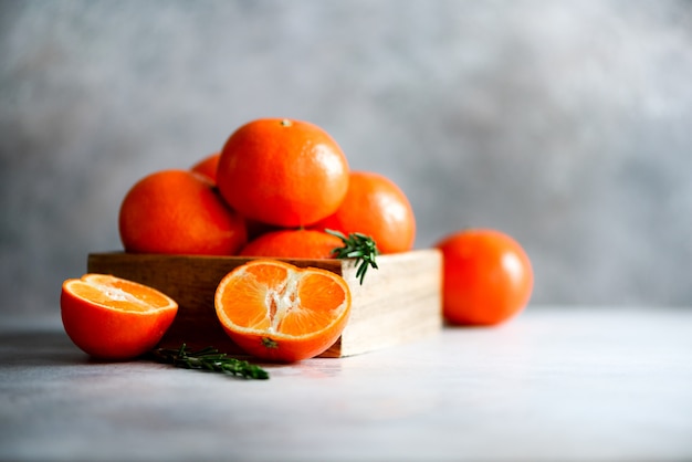 Laranja tangerinas, mandarinas, clementinas, frutas cítricas com alecrim em caixa de madeira