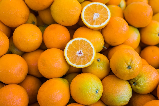 Laranjas cortadas ao meio sobre a pilha de frutas