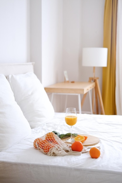 Laranjas e sumo de laranja num copo numa cama branca
