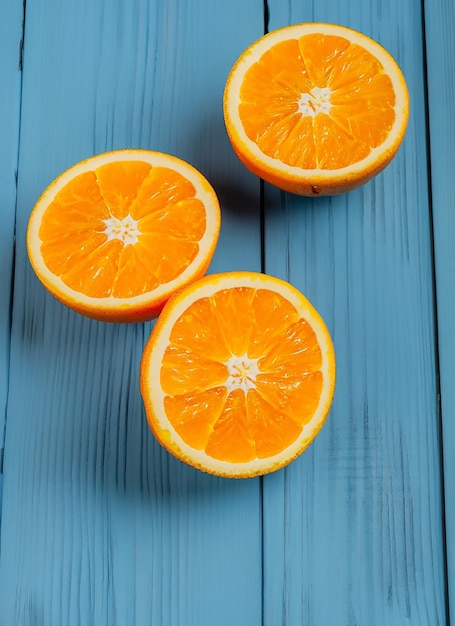 Laranjas orgânicas frescas em meias frutas em fundo de madeira azul com espaço de cópia