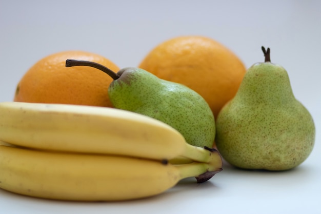 Laranjas, peras e bananas em um fundo branco e isolado