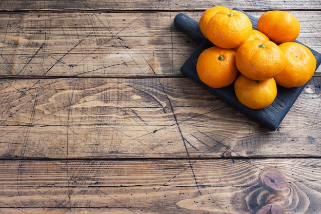Laranjas, tangerinas ou tangerinas clementinas, frutas cítricas em fundo de madeira rústico, copie o espaço.