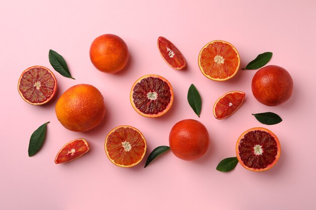 Laranjas vermelhas e folhas em fundo rosa isolado