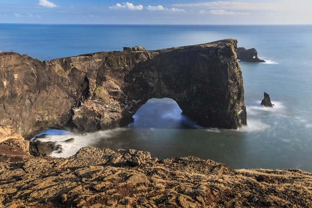 Foto larga exposición del arco dyrholaey con agua suave.