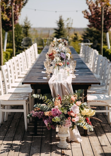 Larga mesa de madera decorada con flores para una boda al aire libre