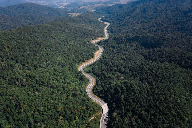 Largo camino curvo en el valle que conecta el campo en la selva tropical y el verde bosque de colinas en la parte más septentrional de Tailandia