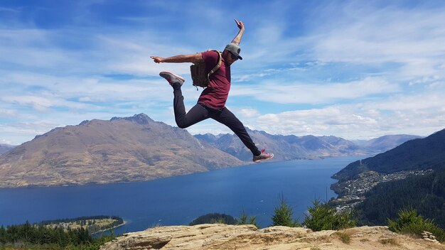 Foto el largo de un hombre saltando en la montaña contra el cielo