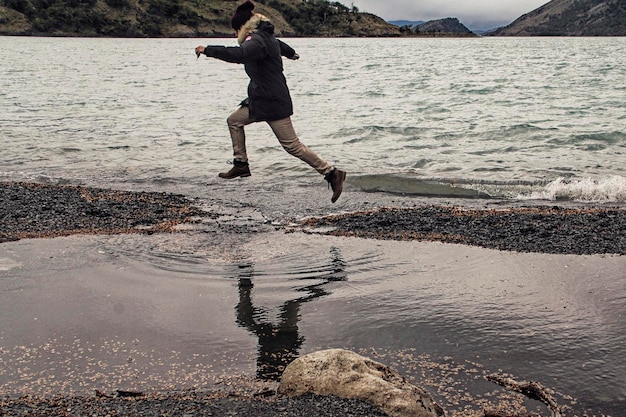 Foto el largo de un hombre saltando en la playa