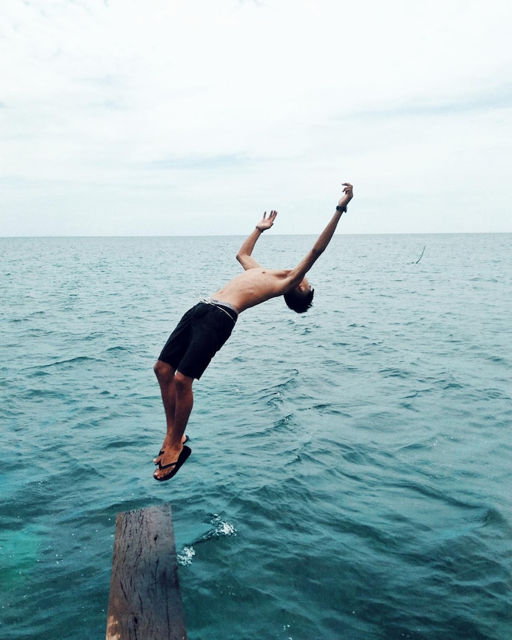 Foto el largo de un hombre saltando sobre el mar contra el cielo