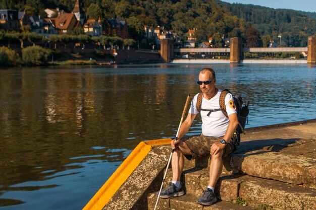 Foto el largo de un hombre sentado junto al lago