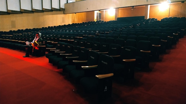 Foto el largo de un hombre sentado en un teatro vacío