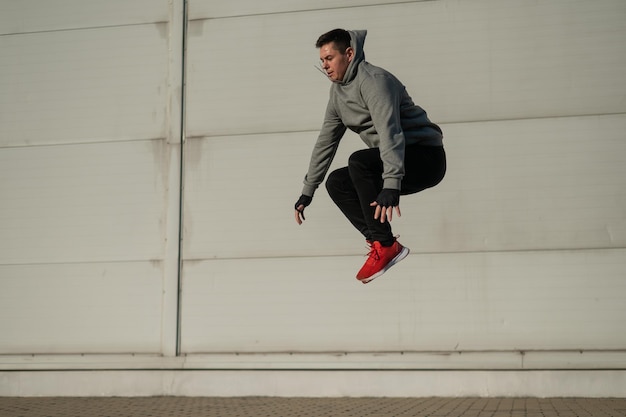 El largo de un joven de pie contra la pared