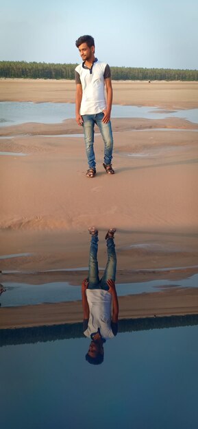 Foto el largo de un joven de pie en la playa