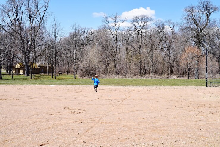 Foto largura completa de niño corriendo por el camino de tierra contra árboles desnudos