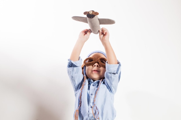 Foto largura completa de un niño con gafas de sol de pie contra un fondo blanco