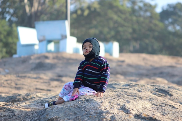 Foto largura completa de un niño con ropa cálida mientras está sentado en la playa