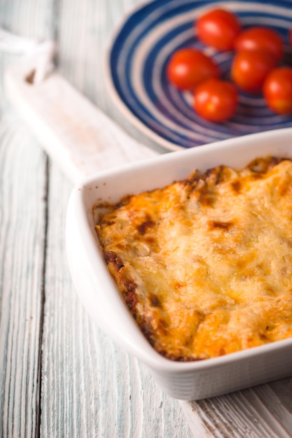 Foto lasagna de carne casera y tomate en un soporte de madera vertical