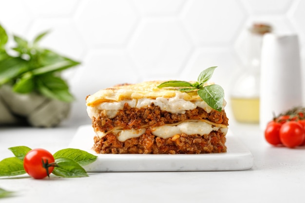 Lasagne Hausgemachte italienische Lasagne mit Bolognese-Fleischsoße Bechamelkäse und Basilikum auf weißem Brett