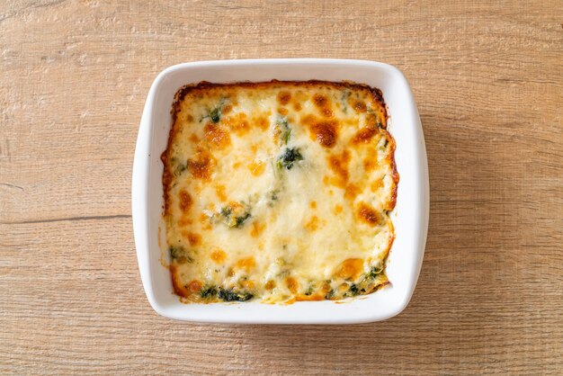 Lasaña de espinacas al horno con queso en placa blanca.