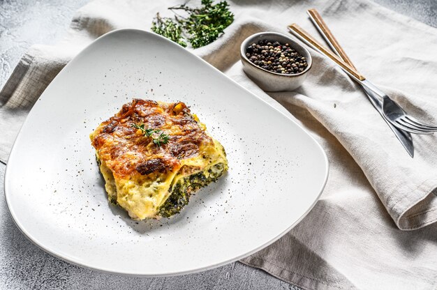 Lasaña de espinacas en un plato, comida vegetariana. Fondo blanco. Vista superior.