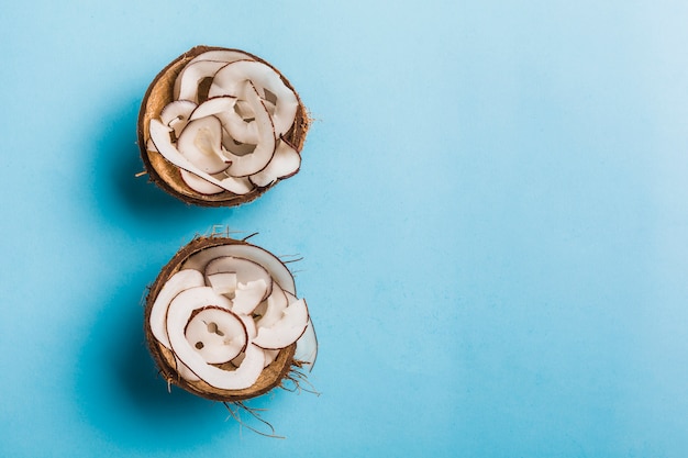 Lascas de coco em uma tigela de coco em um azul