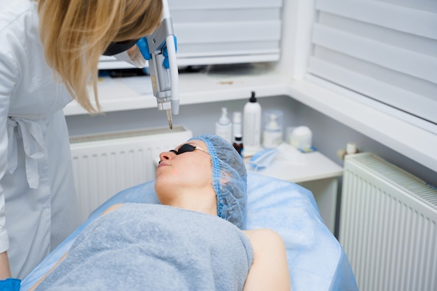 Laser-Photorejuvenation und Carbon Peeling des Gesichts für Frauen. Schwarze Gesichtsmaske. Dermatologie und Kosmetologie. Mit einem chirurgischen Laser.