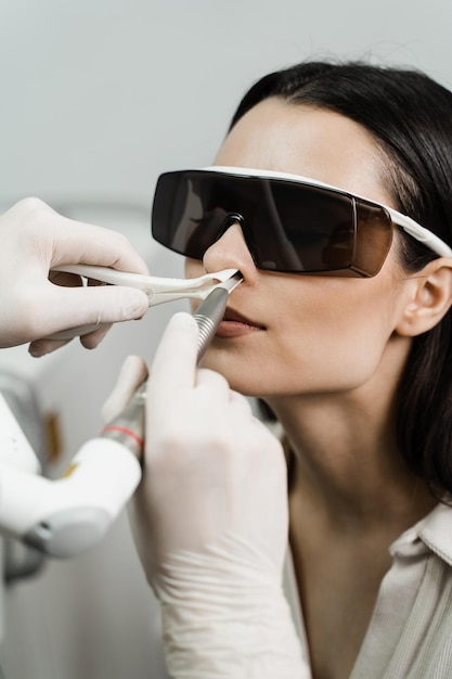 Laserbehandlung Entzündung der Nasenschleimhaut, laufende Nase, Niessymptome Laserbehandlung chronischer Rhinitis HNO-Arzt mit Laser behandelt Patientin mit Schutzbrille