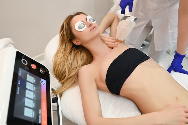 Laserepilation und Kosmetologie im Schönheitssalon. Verfahren zur Haarentfernung. Konzept für Laser-Epilation, Kosmetologie, Spa und Haarentfernung. Schöne blonde Frau, die das Haar entfernt auf Achselhöhlen erhält