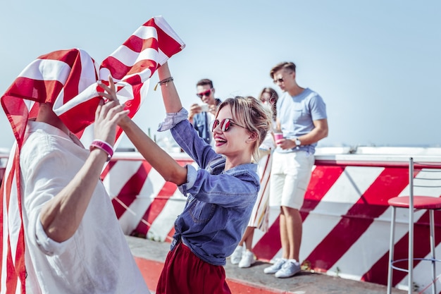 Lass uns tanzen. Charmante Frau, die in halber Position steht, während sie amerikanische Flagge hält